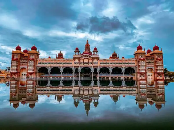 The beautiful Mysore palace of India under cloudy sky making mirror reflection in water