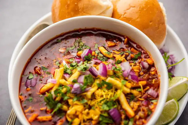 Misal pav is a popular Maharashtrian street food of usal, sprouts curry, topped with onions, tomatoes, farsan and chutney