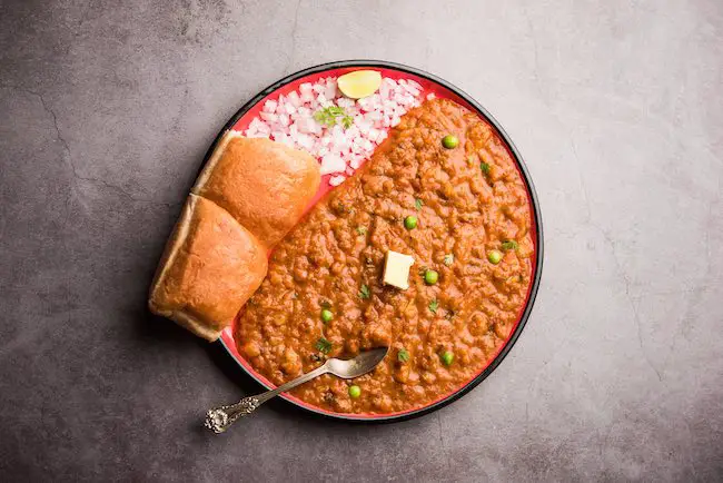 Mumbai Style Pav bhaji is a fast food dish from India, consists of a thick vegetable curry served with a soft bread roll, served in a plate